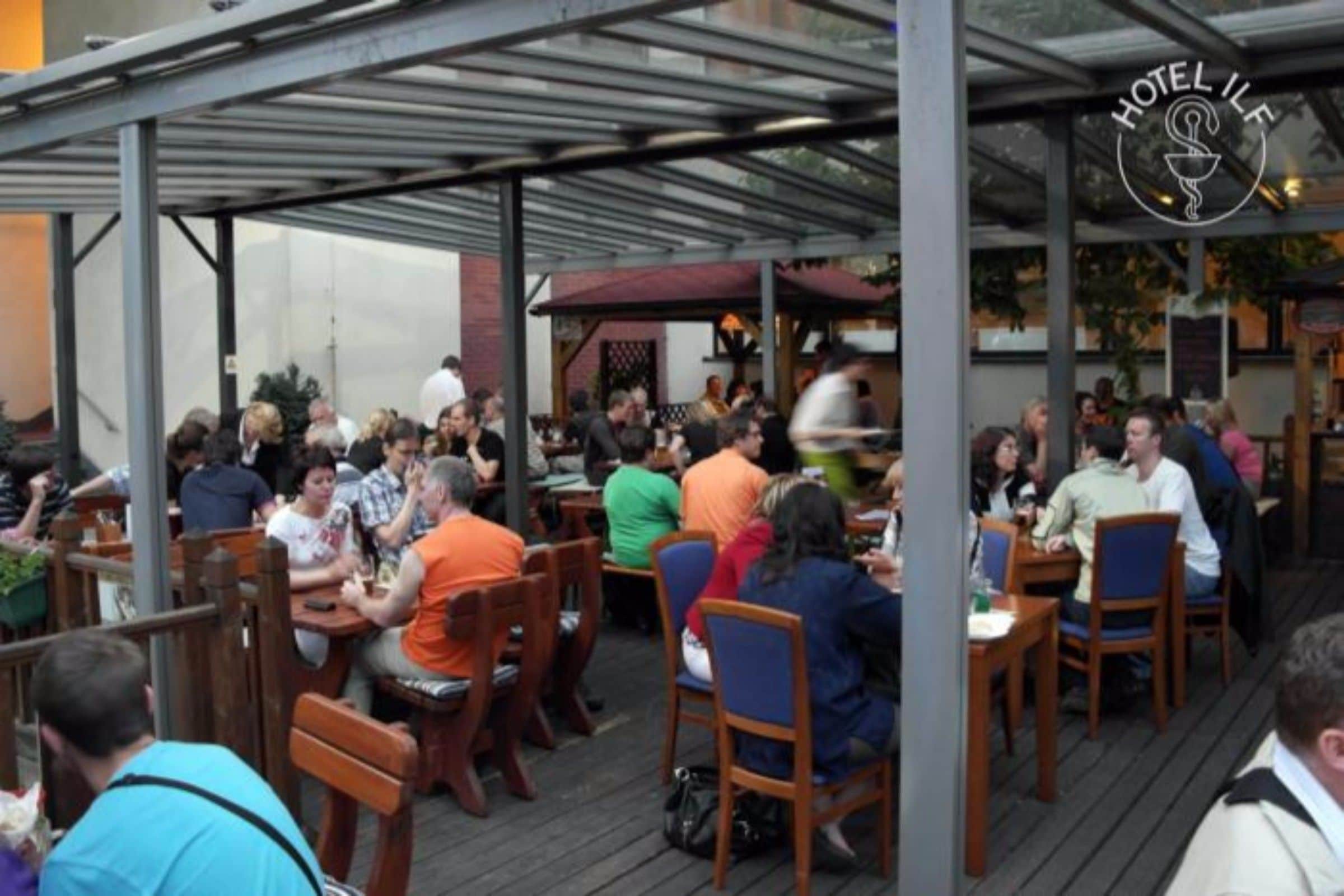 Un restaurant doté d’une terrasse, protégée par un toit en métal, et d’une enseigne indiquant « HÔTEL IFL ».