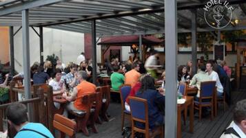 Un restaurant doté d’une terrasse, protégée par un toit en métal, et d’une enseigne indiquant « HÔTEL IFL ».