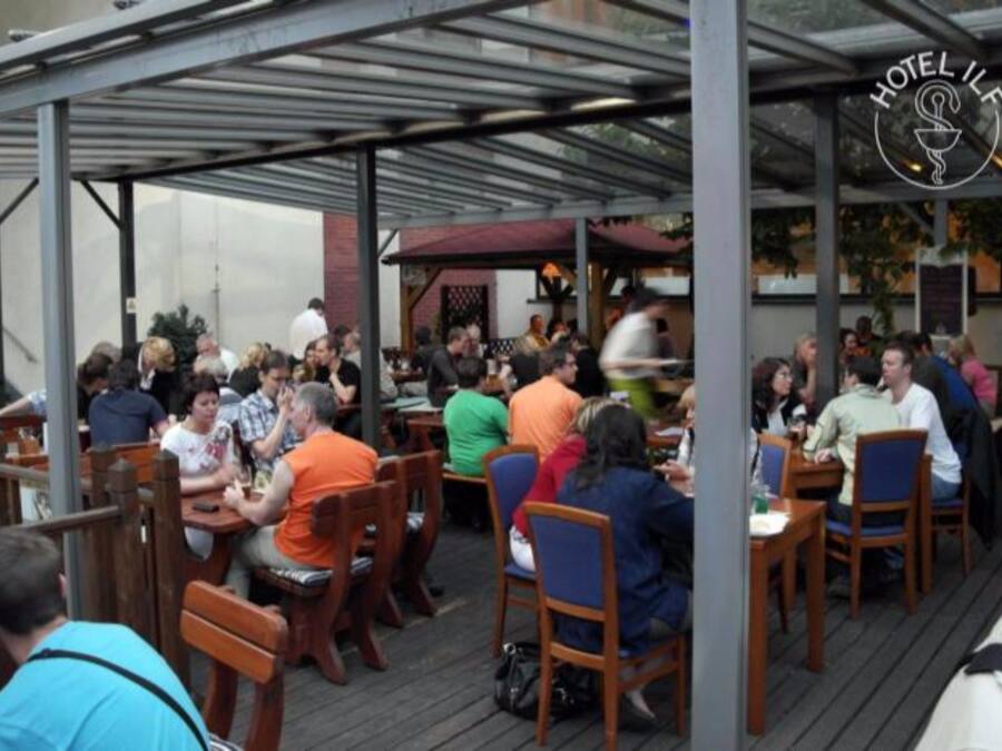 A restaurant with outdoor seating, covered by a metal roof, and a sign reading "HOTEL IFL".