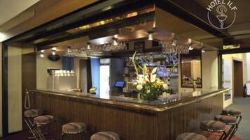 Una zona de bar con mostrador de madera, taburetes y un arreglo floral.