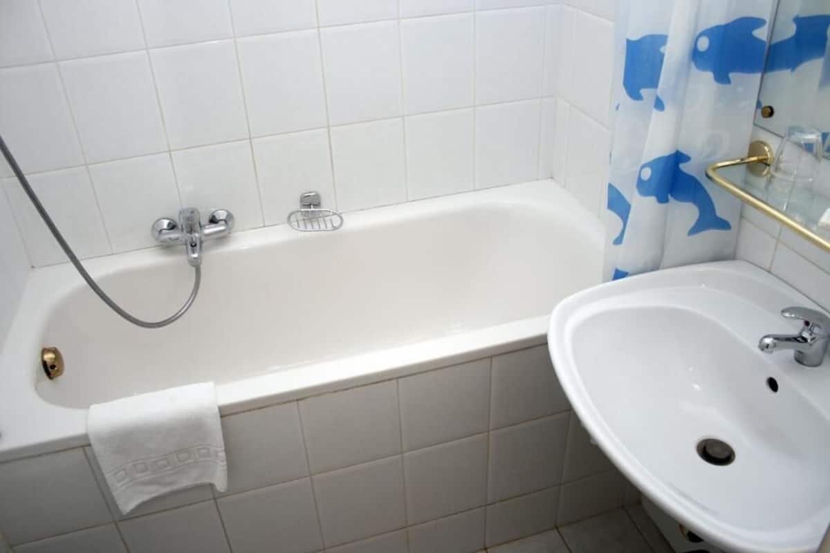 A bathroom with a bathtub, a sink, and a shower curtain with a dolphin pattern.