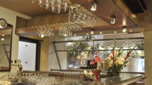 A bar area with a polished granite countertop, hanging crystal chandeliers, and a view of the outdoors through large windows. - ILF Hotel Prague (Prague)