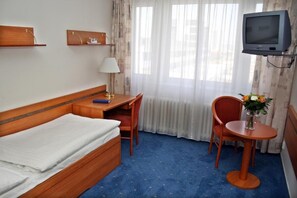A hotel room with a bed, a desk, a chair, a TV, and a window with curtains. - ILF Hotel Prague (Prague)