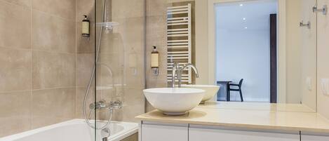 Un baño moderno con una bañera, un espejo grande y un lavabo.