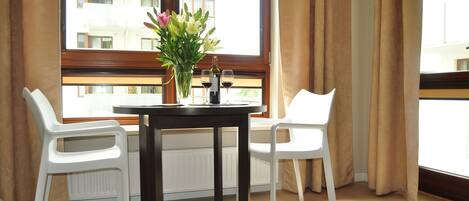 A dining area with a table and two white chairs, a vase with flowers, and two wine glasses.