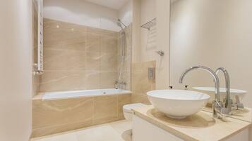 A modern bathroom with a bathtub, a large sink, and a toilet.