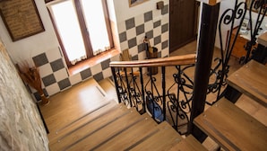 Una escalera de madera con un diseño de cuadros en la pared, una ventana con cortinas y una barandilla de metal.