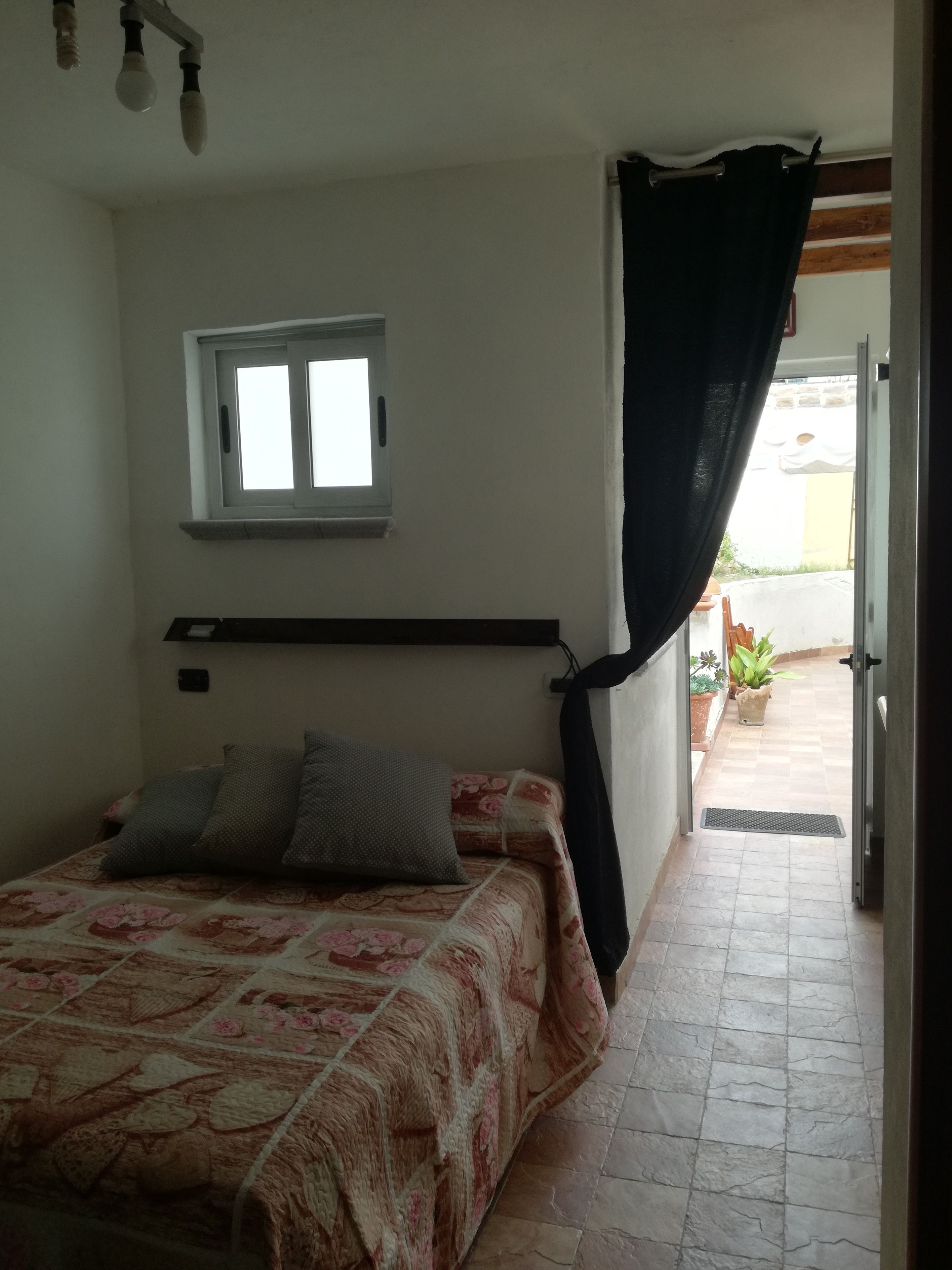 Een slaapkamer met een bed, een raam en uitzicht op de omgeving.