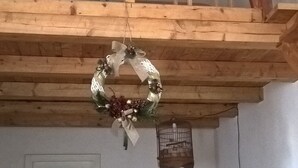Una habitación con cama tipo altillo, una pequeña escalera de madera, barandilla de cristal, una puerta y una jaula de pájaros fijada a la pared.