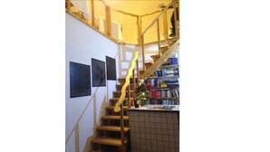 Una escalera con barandilla de madera que lleva a una plataforma con una estantería y un pequeño árbol de Navidad.
