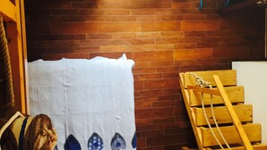 Una habitación con pared de ladrillo, una escalera de madera y una toalla blanca con motivos florales.
