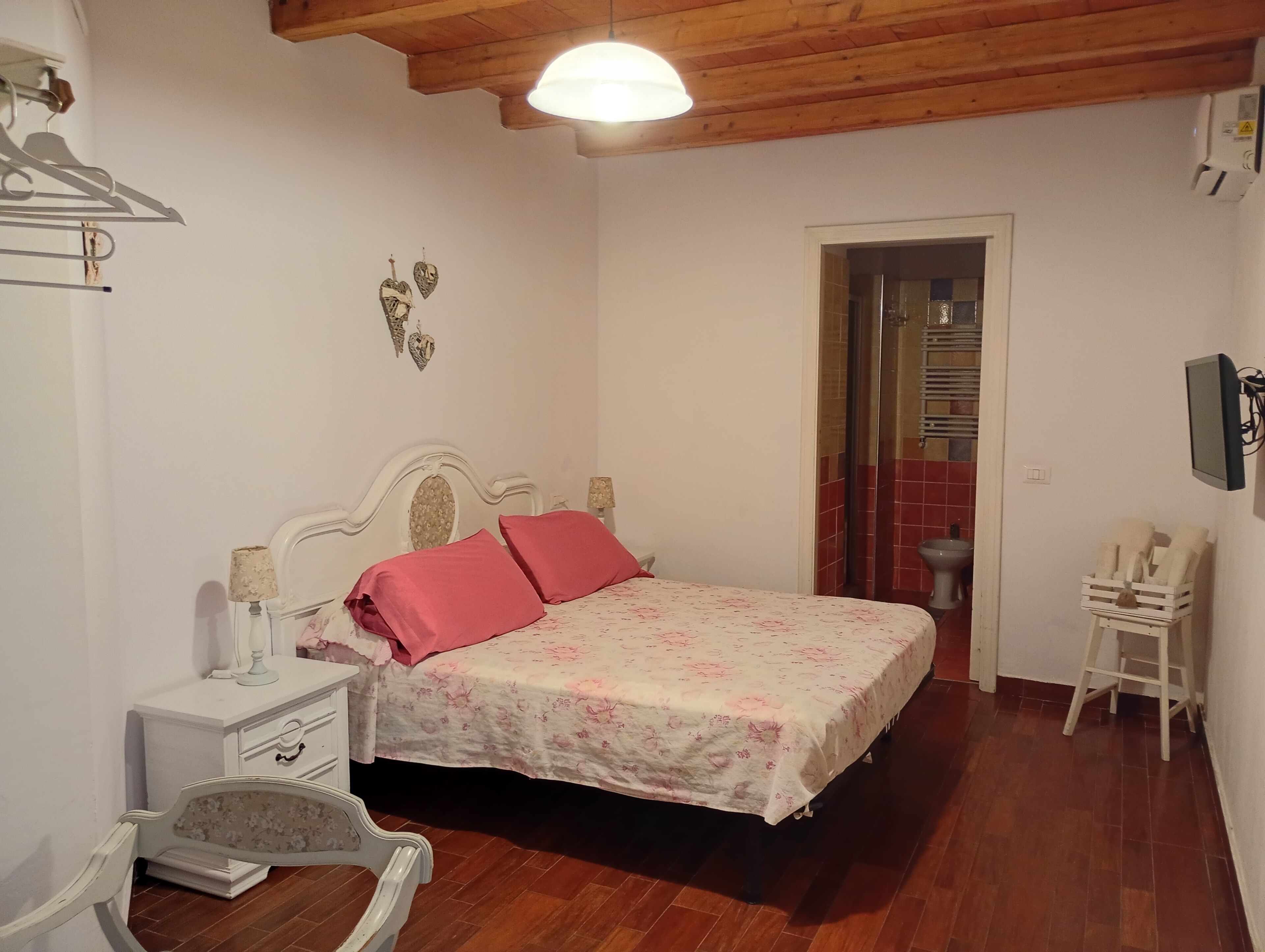 A bedroom with a bed, bedside table, lamp, and a wardrobe.