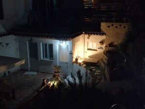A small, dimly lit courtyard with a tiled floor, a few potted plants, and a small outdoor seating area. - B&B PompeiLog (Torre Annunziata)