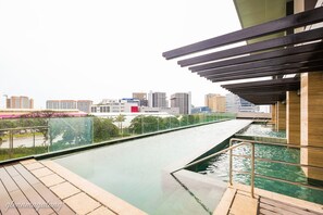 A rooftop pool with a city skyline view, a pergola, and a glass railing. - Somerset Alabang Manila (Muntinlupa)