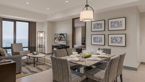 A modern dining area with a glass table, cushioned chairs, and a city view.