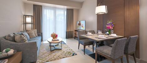 A modern living room with a sofa, coffee table, dining table, and chairs.