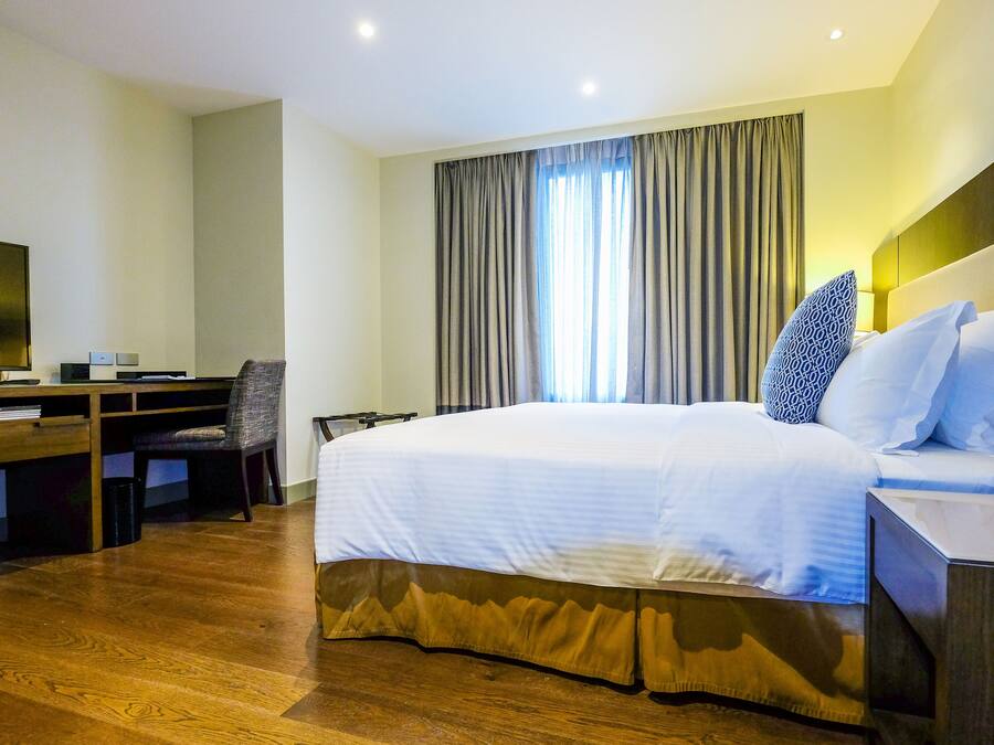 Una habitación de hotel con una cama grande, un escritorio con televisor y una silla.