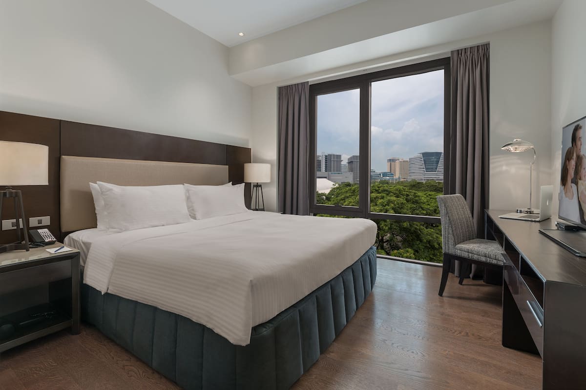 A hotel room with a large bed, a desk with a laptop, a chair, and a TV.
