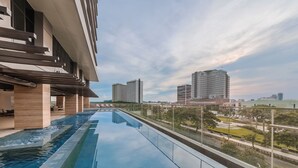 A modern hotel with a rooftop infinity pool, offering views of the city skyline.