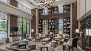 A spacious lobby with a large seating area, multiple bookshelves, and a modern chandelier.