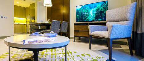 Una habitación de hotel moderna con comedor, televisión y sofá.