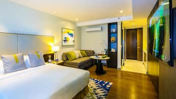 A hotel room with a large bed, a sofa, a small table, and a TV.