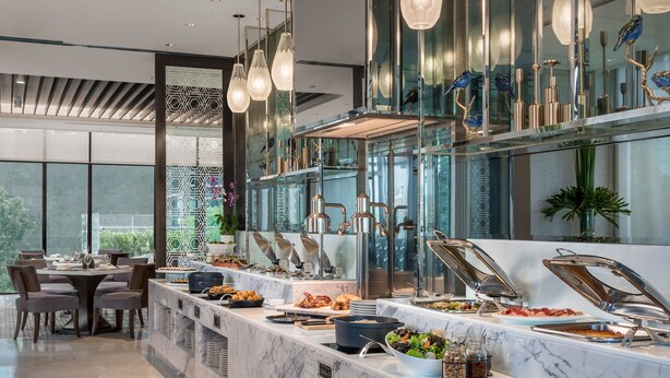 A modern dining area with a marble counter, buffet with various food items, and a seating area with chairs and a table.