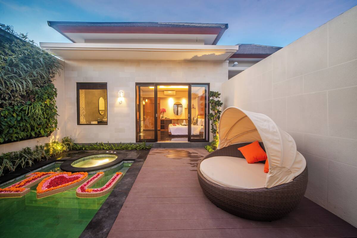 An outdoor pool area with a hot tub, a lounge chair, and a well-maintained garden.