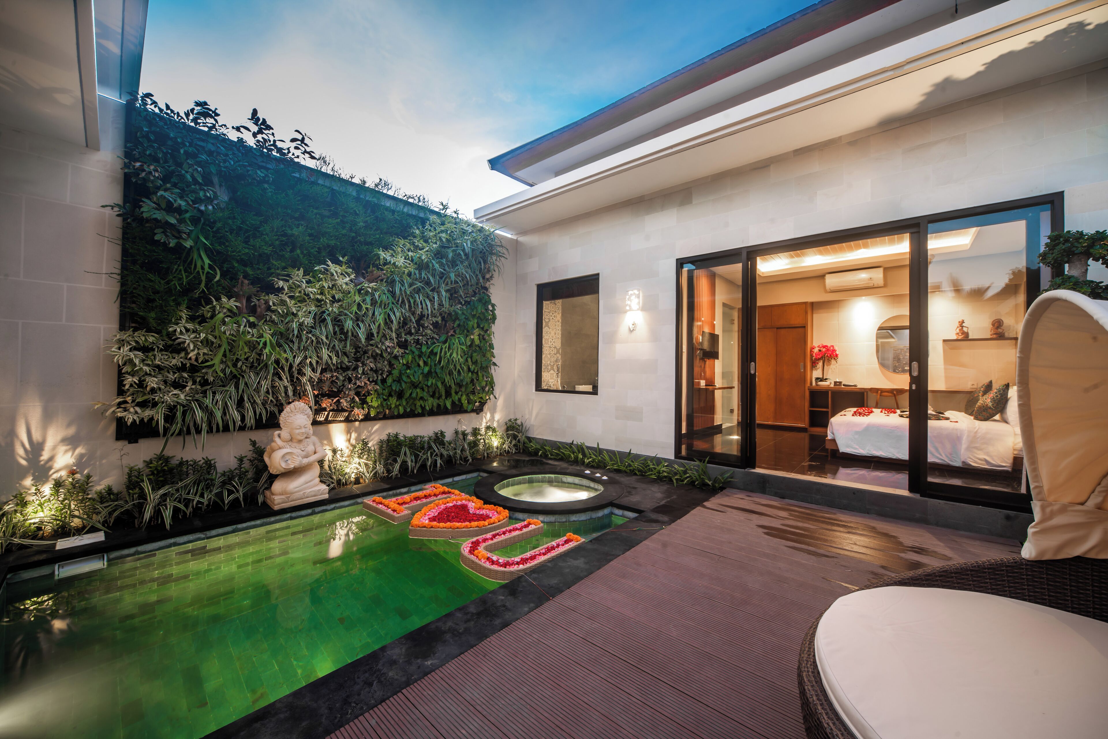 A modern hotel with a private pool, a lush green wall, and a well-lit interior.