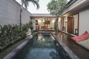A courtyard with a swimming pool, seating area, and a dining space. - Gaing Mas Jimbaran Villas by Gaing Mas Group (Jimbaran)