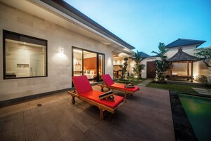 Una casa moderna con piscina, dos sillones de descanso y un interior bien iluminado.