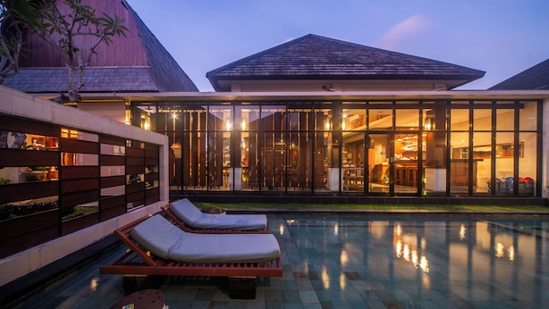 Un moderno resort con piscina, tumbonas y un amplio frente de cristal.