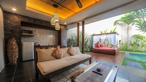 Un espacio habitable moderno con sofá, una mesa de comedor y una cocina equipada con refrigerador y microondas.