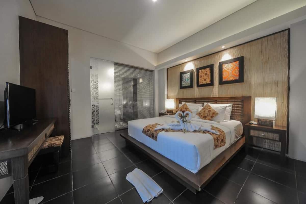 A modern hotel room with a large bed, a desk, and a TV.