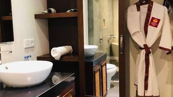 A bathroom with a large white sink, a mirror, a towel, and a robe hanging on a rack.