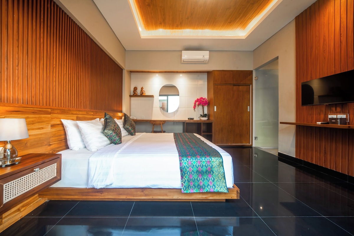 Une chambre d’hôtel moderne dotée d’un grand lit, de lambris en bois, d’un téléviseur à écran plat et d’un petit espace bureau.