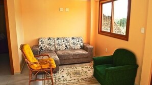 Una sala de estar con un sofá, dos sillones, una alfombra y una ventana con vistas.