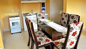 Una cocina compacta con estufa a gas, gabinetes blancos y un lavamanos pequeño.