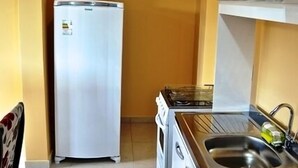 Una cocina compacta equipada con refrigerador, estufa, lavaplatos y microondas.