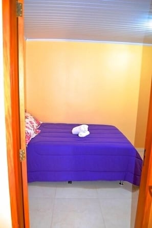 A small, single-bed room with a purple bedspread and a white towel on the bed. - Residencial Daniel (Gramado)