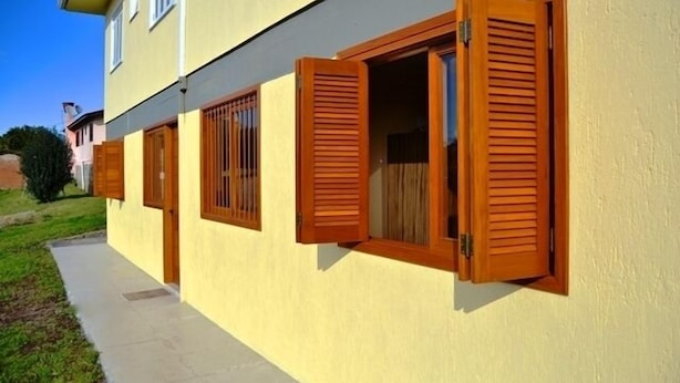 Un edificio de dos plantas con fachada amarilla y contraventanas de madera.