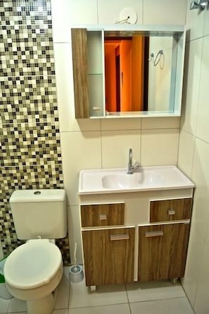 A bathroom with a toilet, sink, and wooden cabinets. - Residencial Daniel (Gramado)