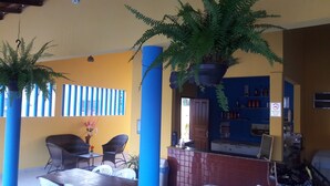 An outdoor seating area with chairs and a table, a blue pillar, and a hanging plant.