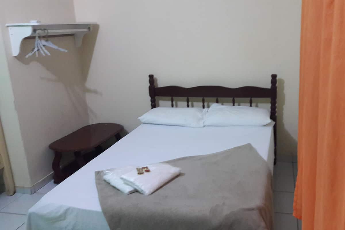 A single bed with white bedding, a wooden headboard, and a small bedside table.