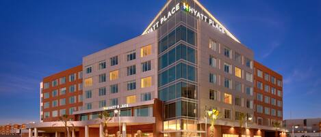 A multi-story hotel with a prominent 'Hyatt Place' sign, featuring a modern design with large windows and a corner entrance.