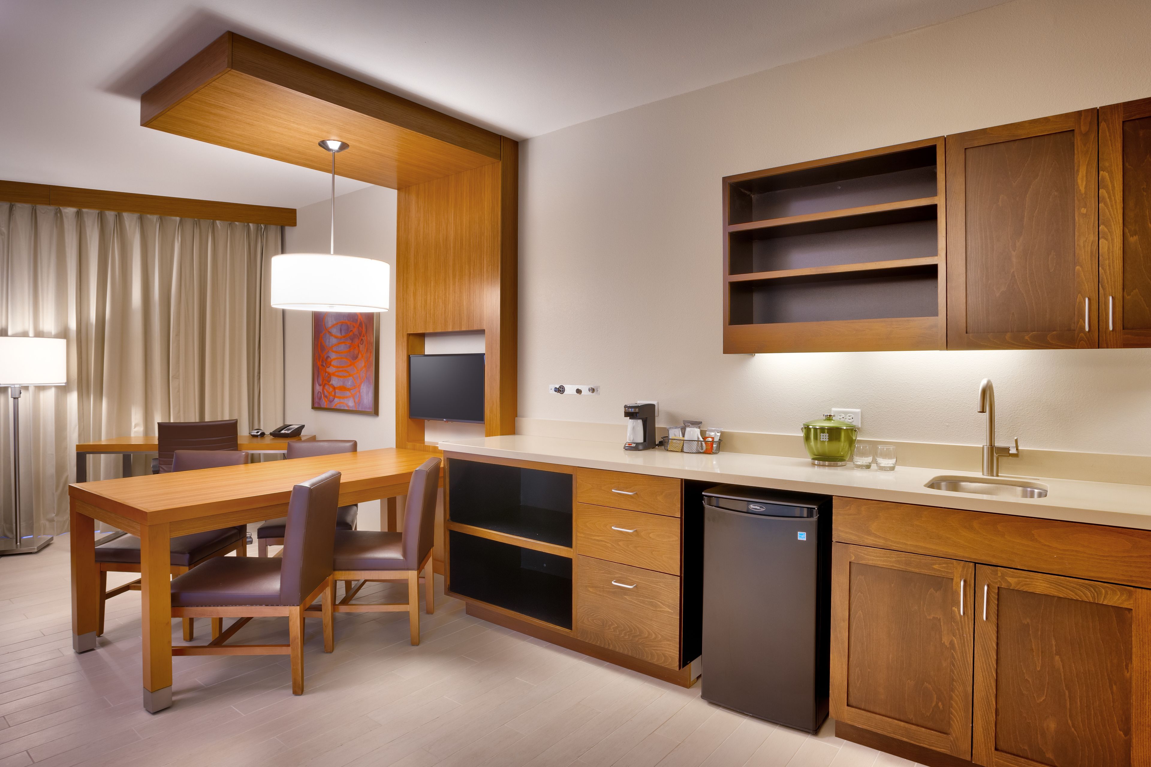 A modern kitchen with wooden cabinets, a built-in dishwasher, and a dining area with a table and chairs.