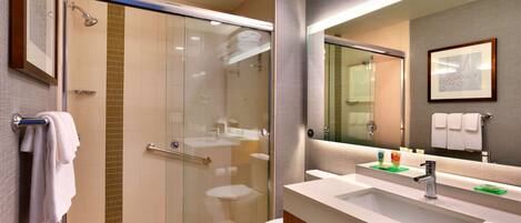 A modern bathroom with a glass-enclosed shower, a white sink, and a large mirror.