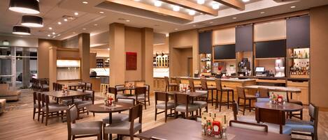 A hotel lobby with multiple seating areas, a bar, and a kitchen area.