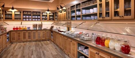 Una cocina con armarios de madera, una encimera larga y diversos utensilios de cocina.