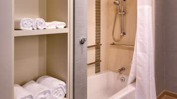 A bathroom with a bathtub, a shower, and shelves with towels.